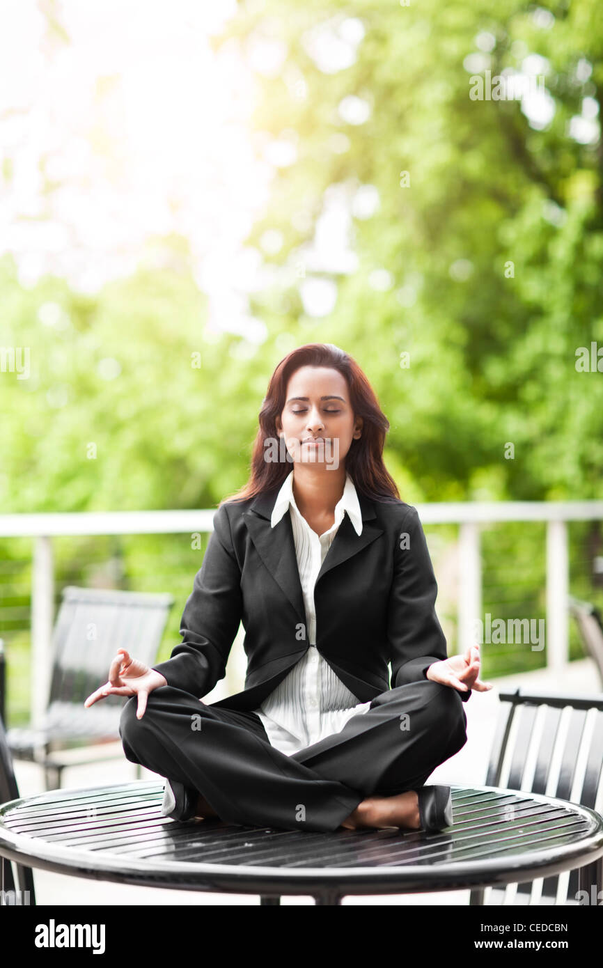 Indian businesswoman practicing yoga on tabletop Stock Photo