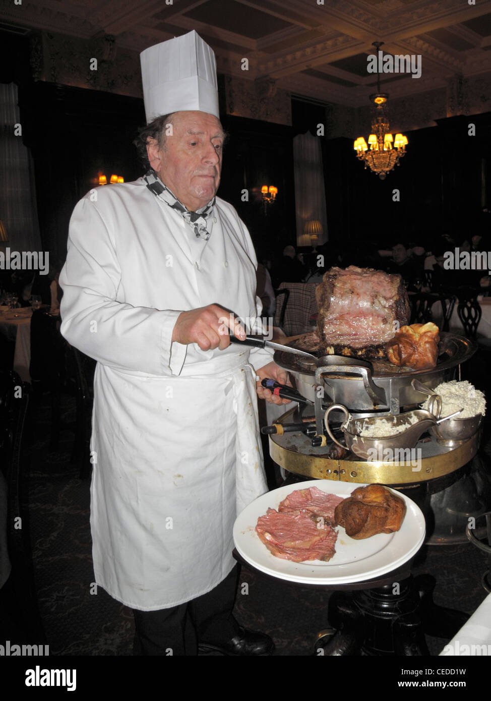 Master carver preparing roast beef dish at the table at Simpson's-in-the-Strand, London, England 111230 x1568 Stock Photo