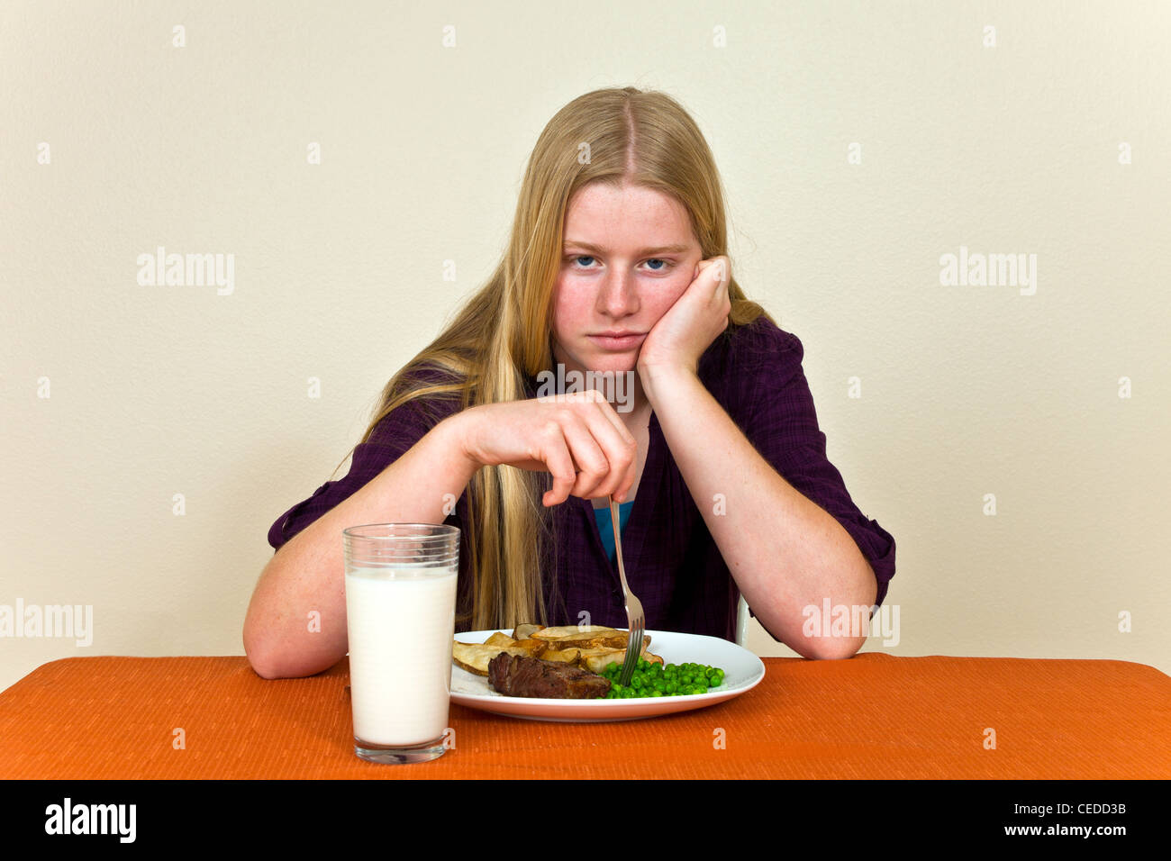 Strong willed stubborn Teenage girl Sitting at table unhealthy attitude towards food dislikes won't eat her dinner eye contact camera MR   © Myrleen Pearson Stock Photo