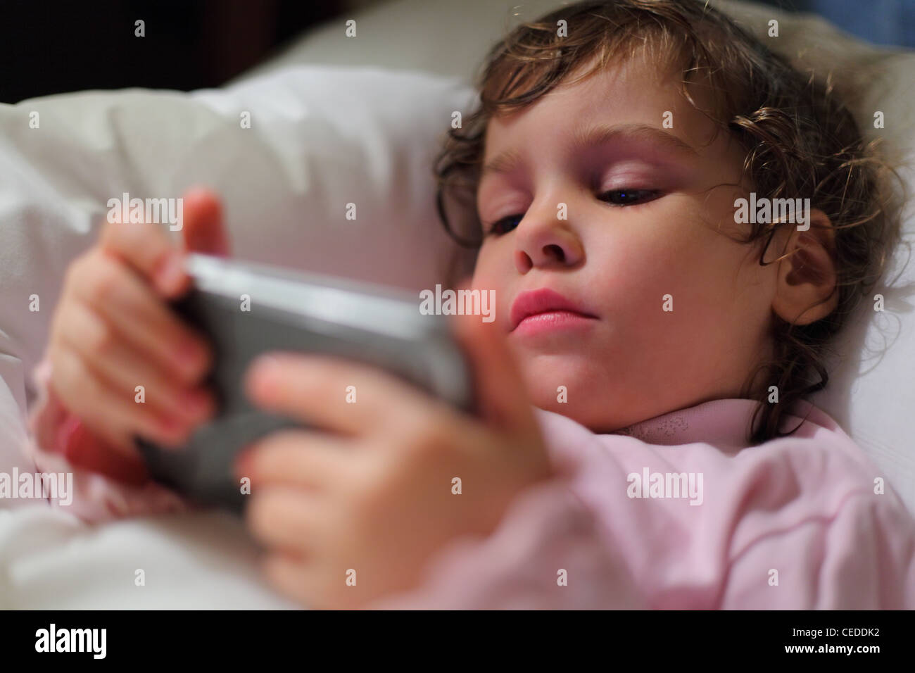 Little girl in bed with hendheld computer Stock Photo