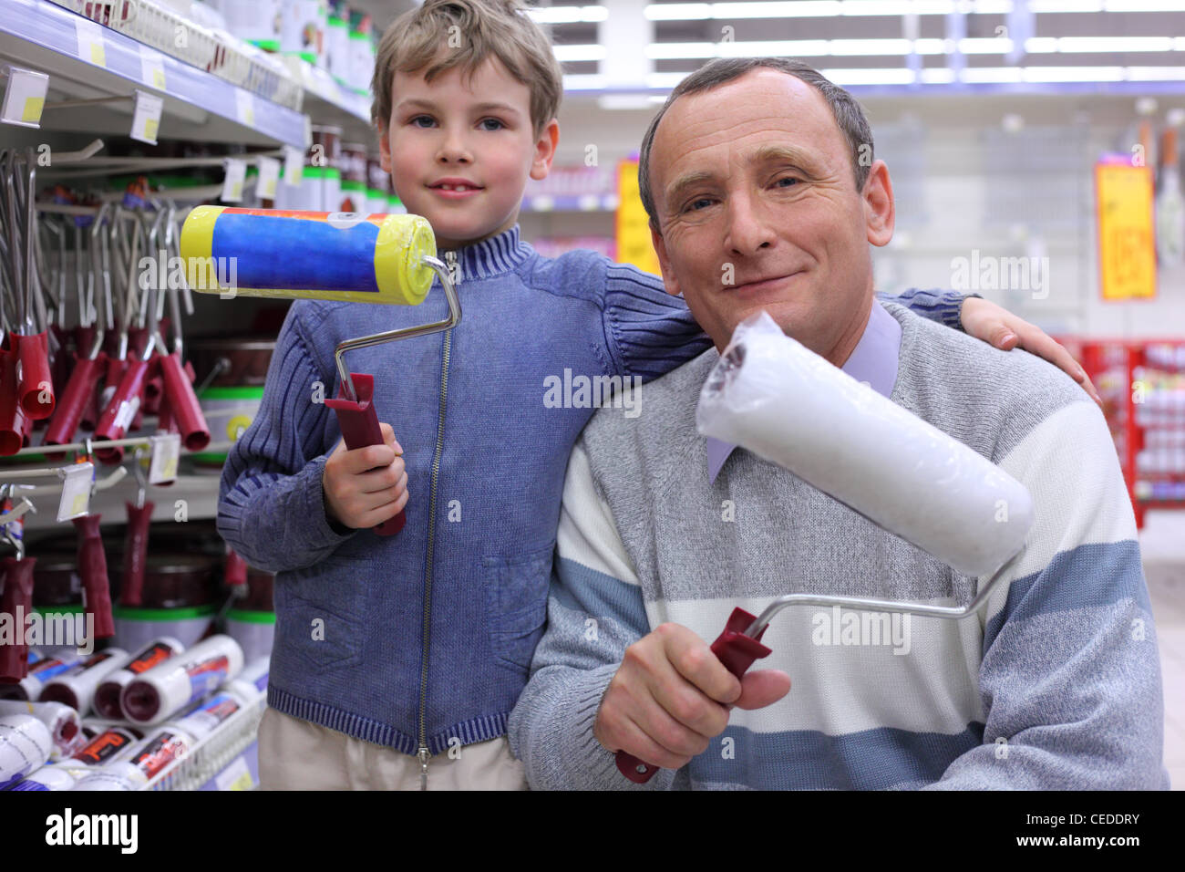 elderly man with  boy in shop with painting rollers in hands Stock Photo