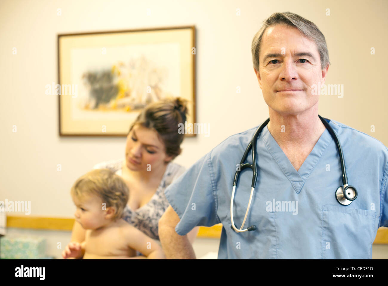 Portrait of doctor in exam room with patient in backgroud Stock Photo