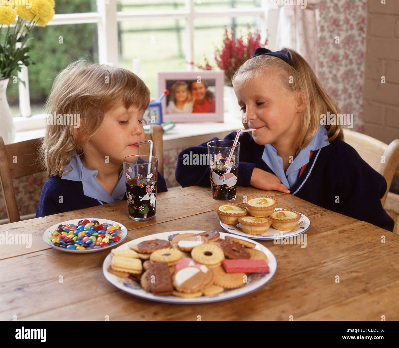 Sisters eating biscuits and drinking soft drinks, Berkshire, England