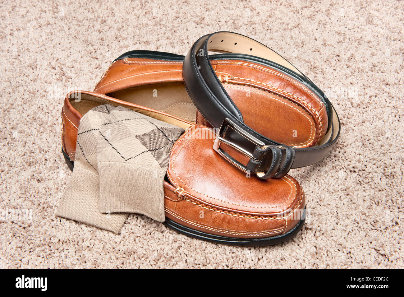 A new pair of tan leather shoes with socks and belt on beige carpet Stock Photo