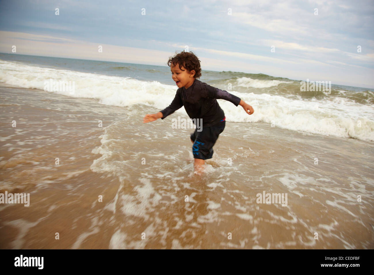 Mixed race boy playing in ocean waves Stock Photo Alamy