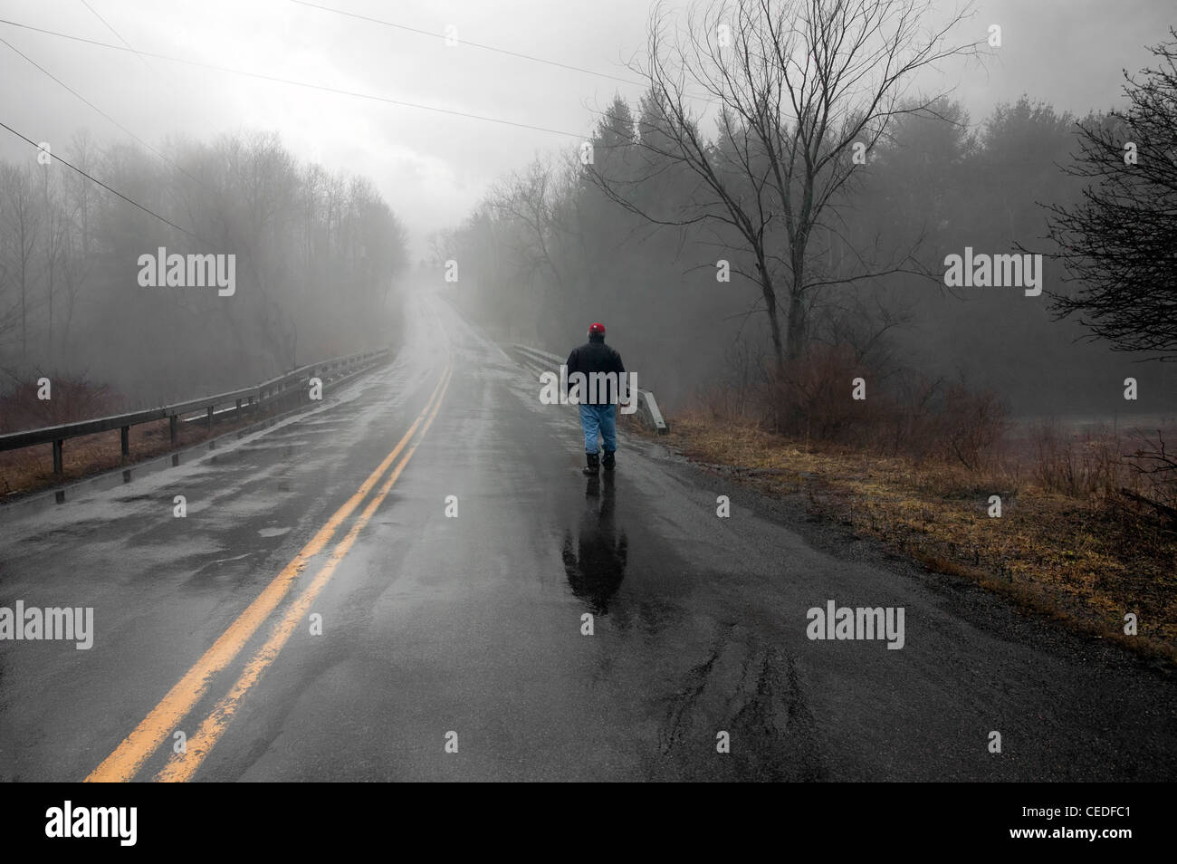 man walking alone in the rain and fog Stock Photo