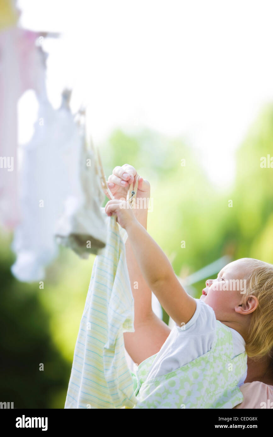 Caucasian mother and baby hanging laundry on clothes line Stock Photo