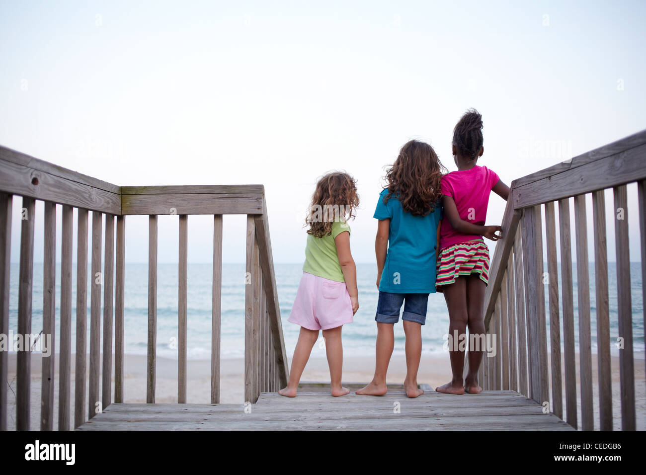 Girls standing together on deck near ocean Stock Photo