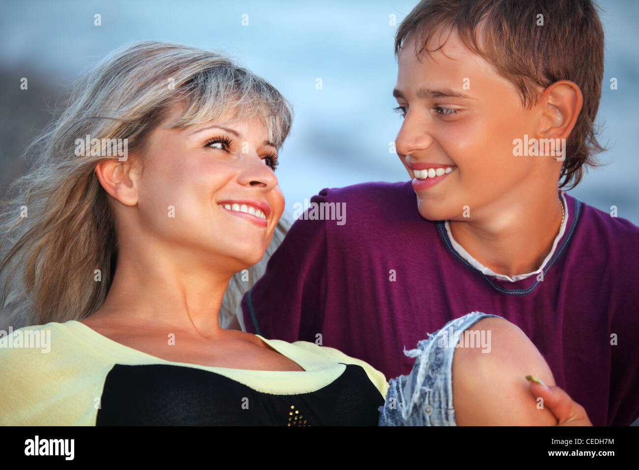 smiling boy and young woman on beach in evening, Looking against each