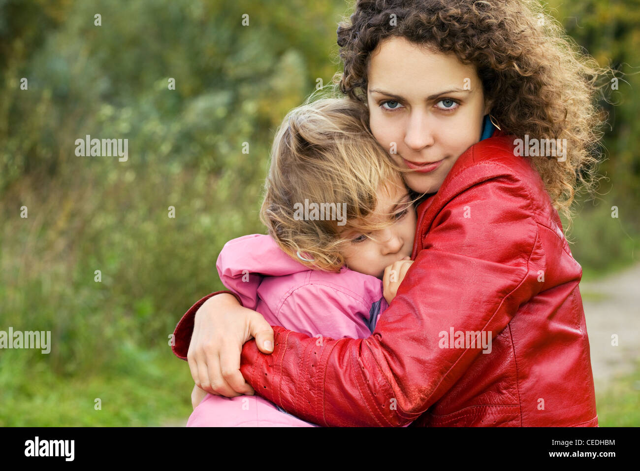 young woman protects little girl from wind in garden Stock Photo