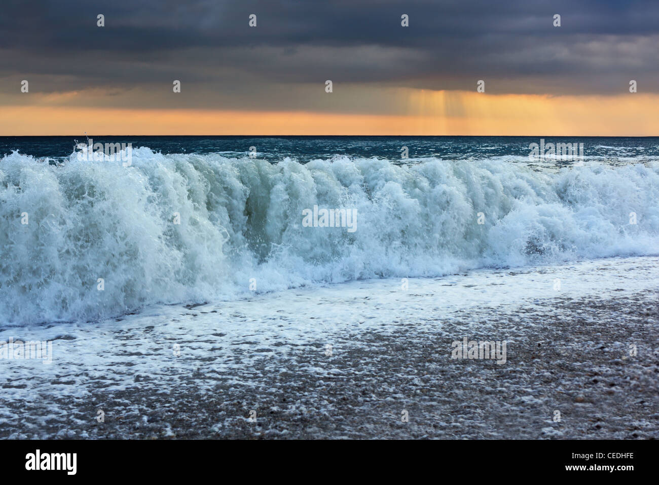 Sea coast with waves, wide angle; sun appeared through clouds Stock Photo