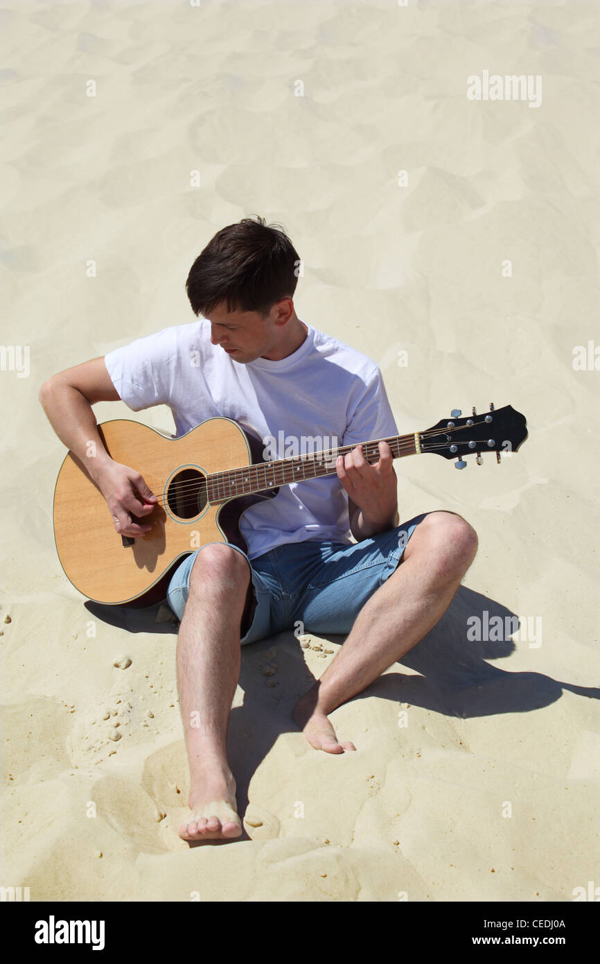 guy plays guitar sitting on sand Stock Photo - Alamy