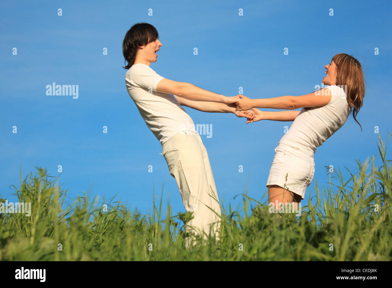 два человека со спины. и людям стоит держаться. пара гуляет. мужчина и женщина идут за руку. подростки идут за руку.