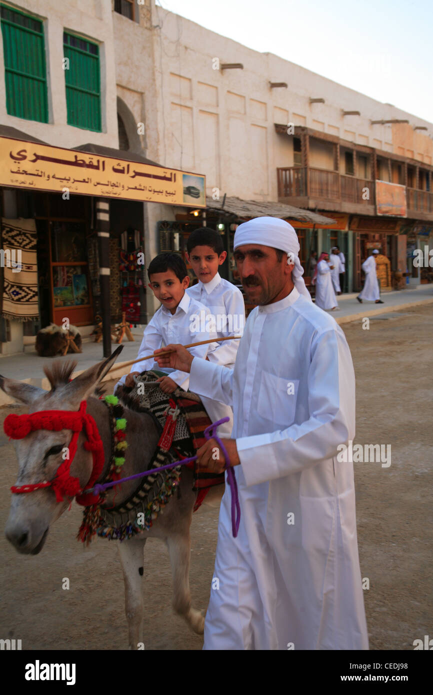 Children riding a donkey in traditional Qatari dress through Doha souk (souq) Qatar Stock Photo
