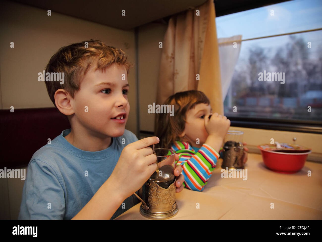 Two children drink tea from glasses in train car Stock Photo Alamy