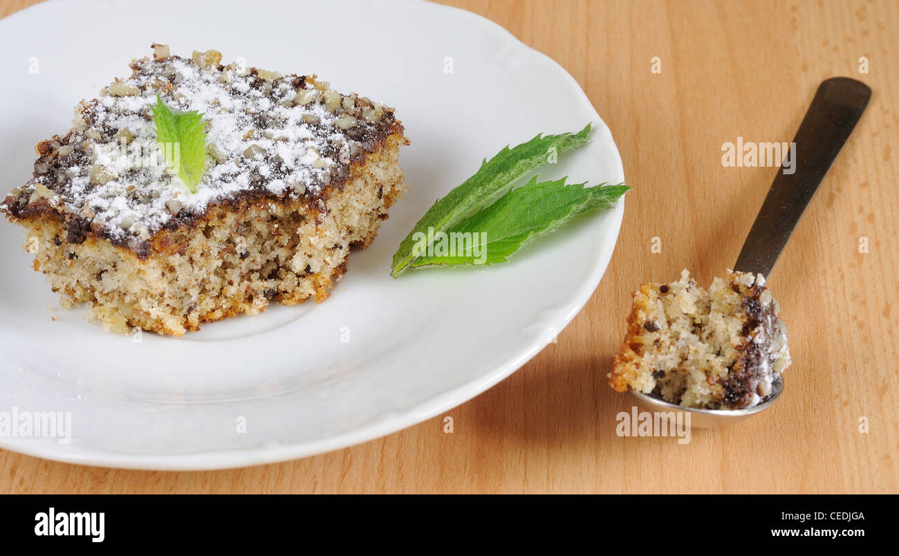 Sweet cake (gingerbread) with chocolate icing, nuts and small mint leaf. Stock Photo