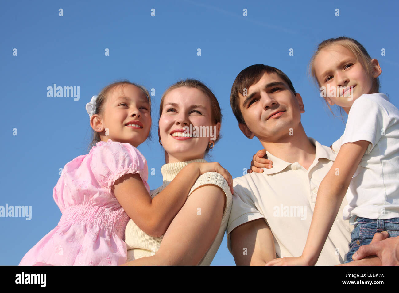 two parents hold children on hands against sky Stock Photo