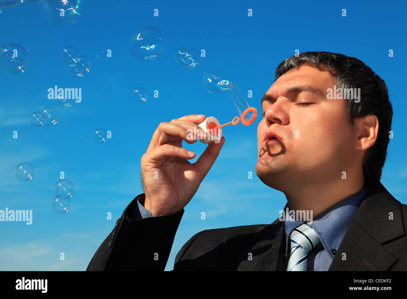 businessman blows soap bubbles against sky Stock Photo