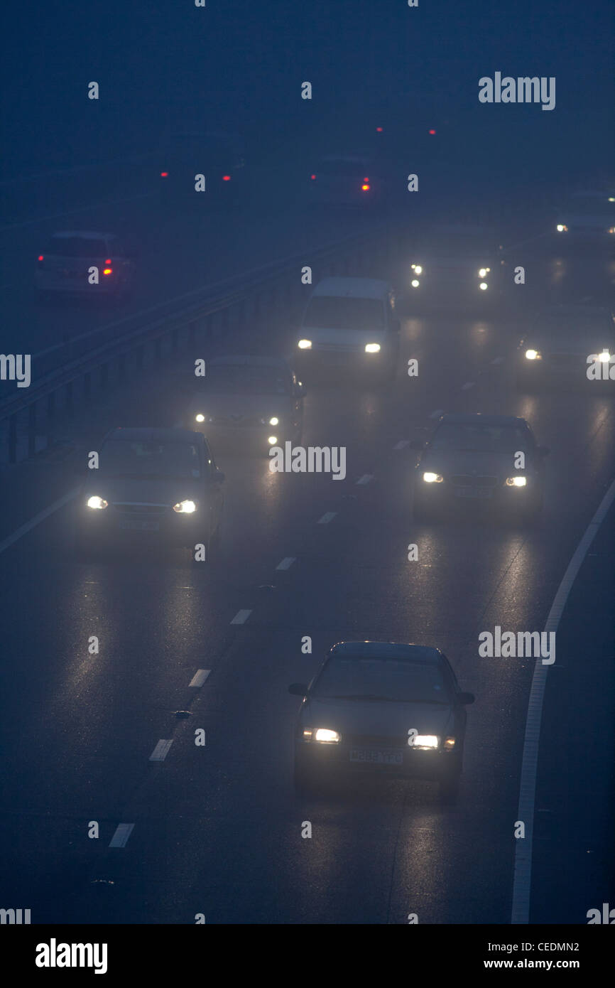 Cars in the fog on road in England at night Stock Photo