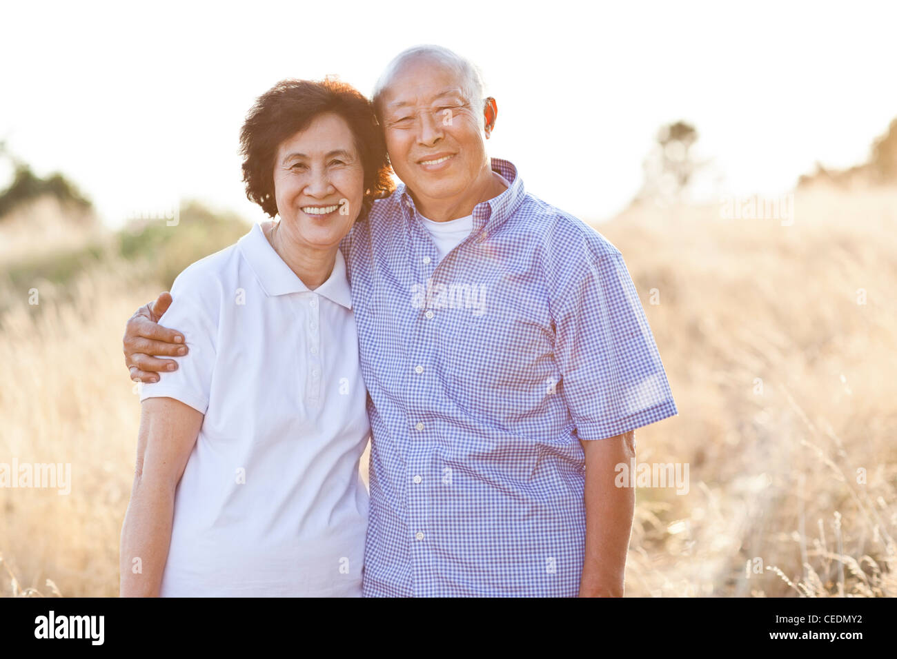 Smiling senior Chinese couple standing in field Stock Photo - Alamy