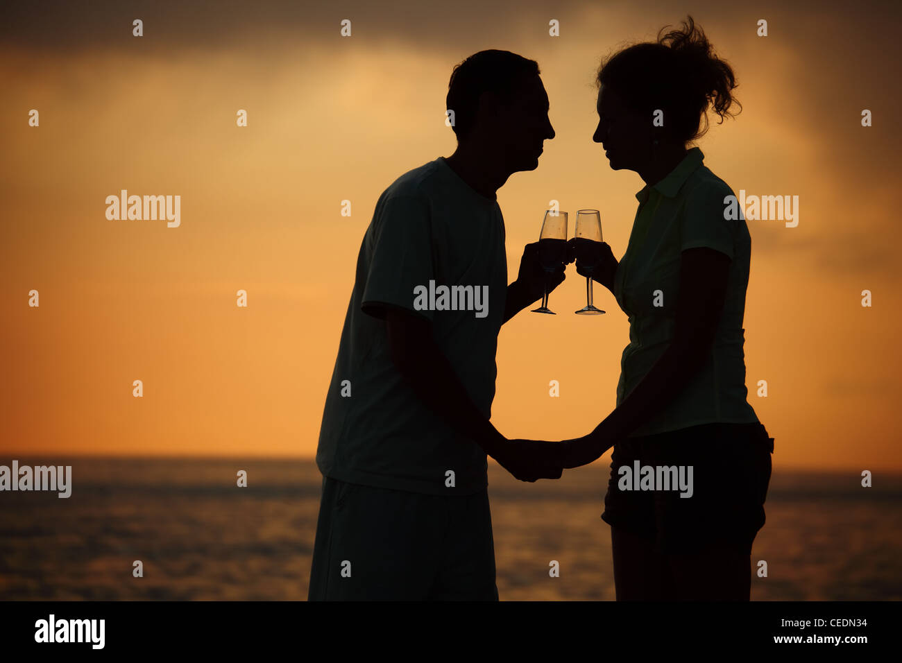 Silhouettes of man and woman with glasses on sea sunset Stock Photo
