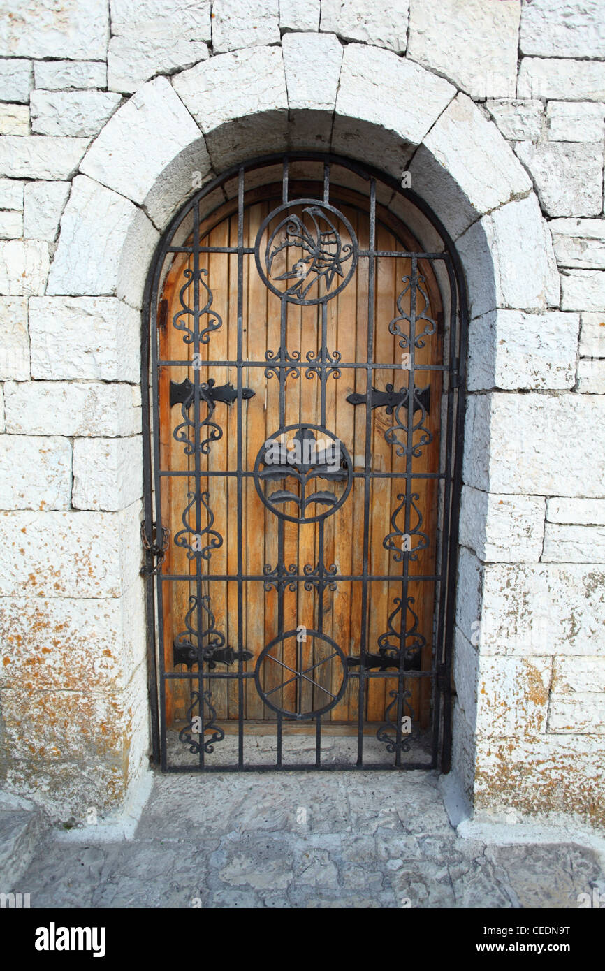 Door behind  lattice in stone wall Stock Photo