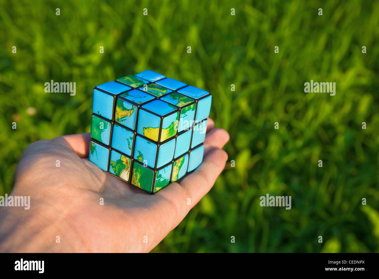 Cube in the manner of planets land on palm on background of the herb Stock Photo
