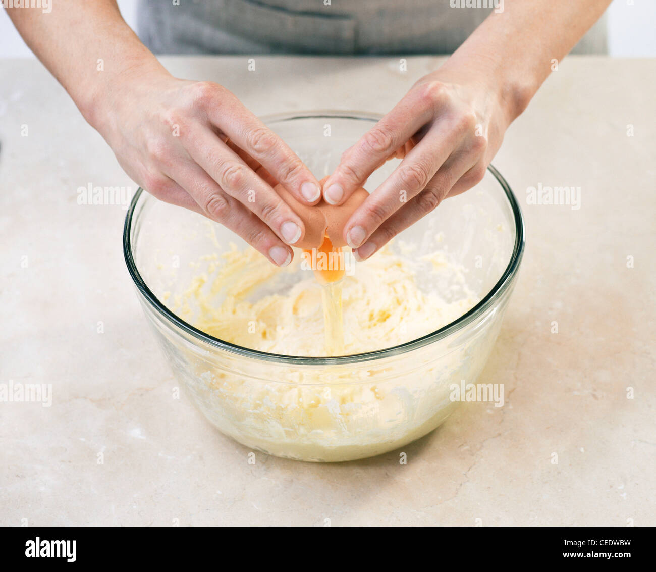 Adding eggs to butter and sugar mixture in bowl Stock Photo