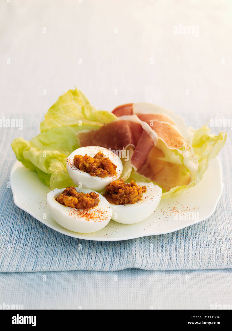 Curried eggs served with lettuce and parma ham Stock Photo