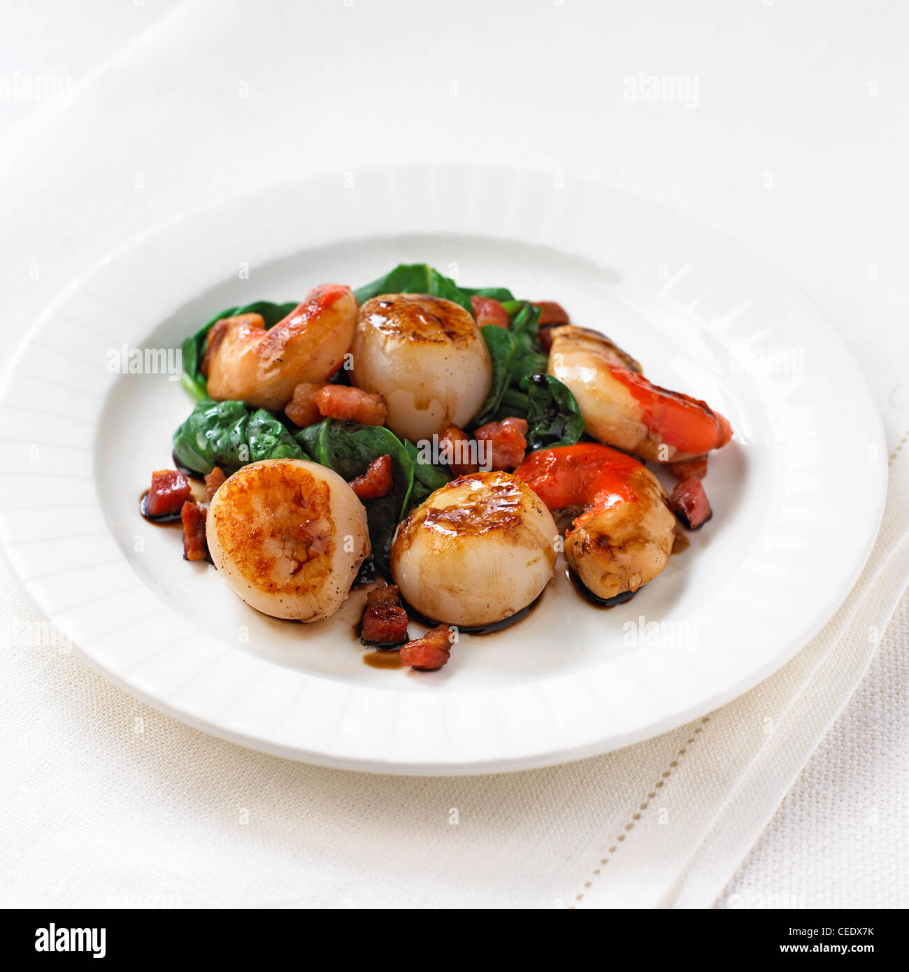 Sauteed scallops with pancetta and wilted spinach Stock Photo