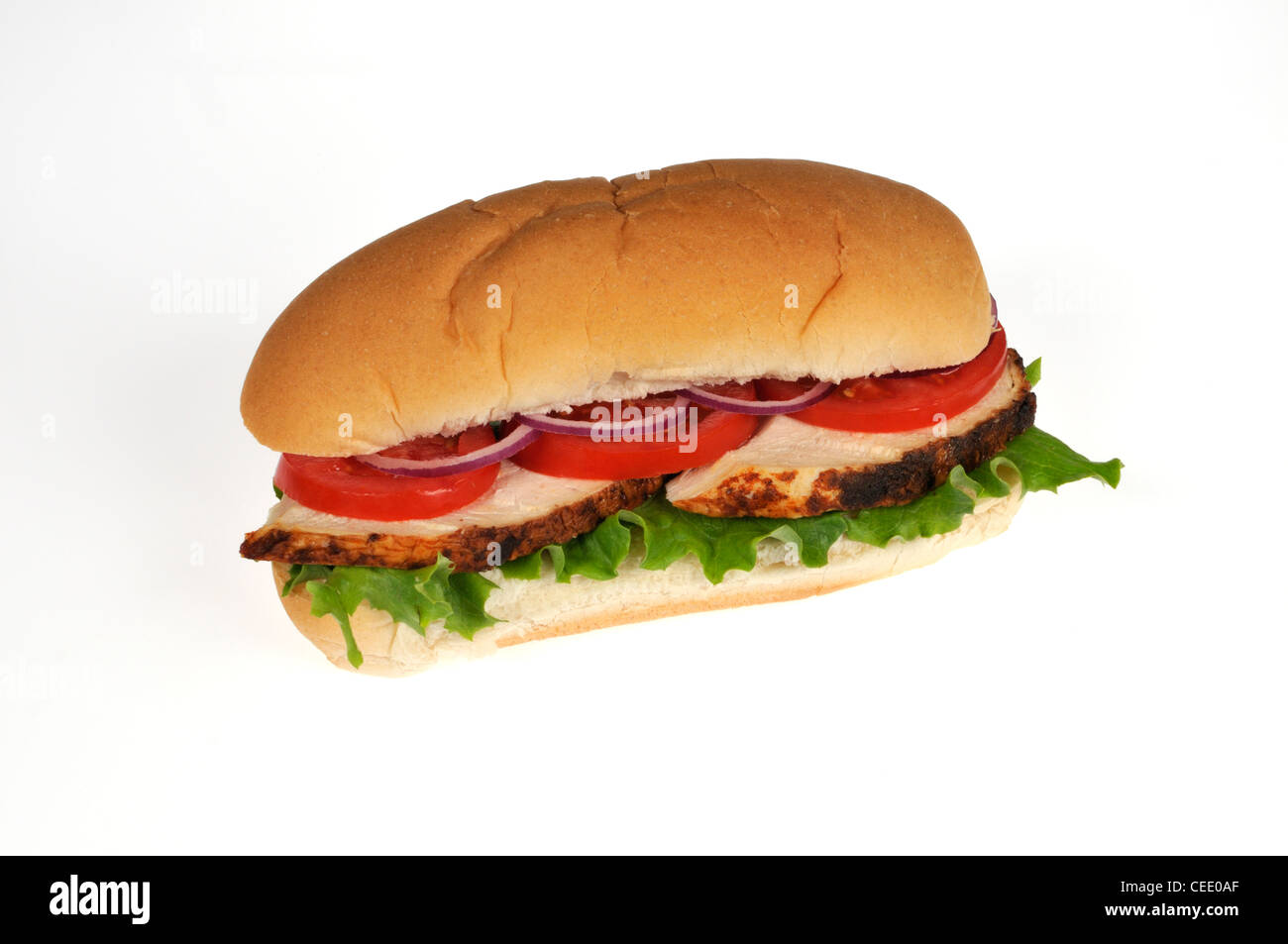 Sliced rotisserie cooked and sliced chicken sub sandwich with lettuce, tomato and red onion in bread roll on white background cutout. Stock Photo