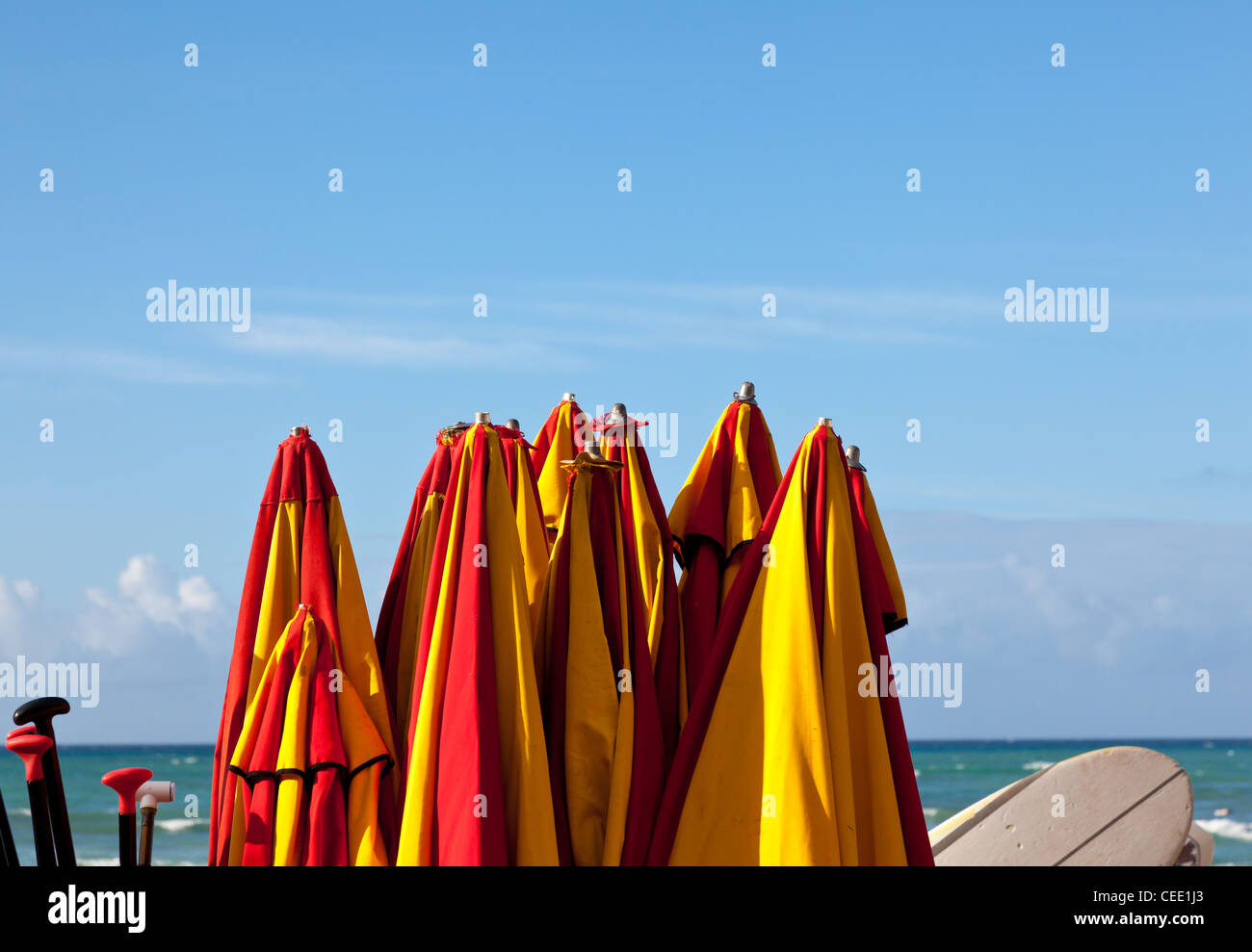 Set of beach umbrellas in a stack by blue ocean Stock Photo