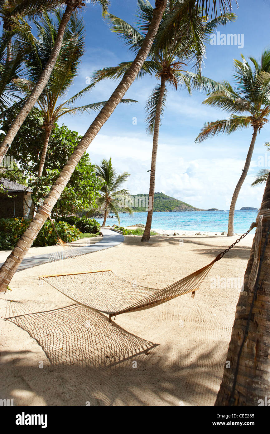 Island paradise beach private exclusive Mustique Caribbean palm trees secluded no people sky sand sea deserted sunny sunshine ocean hammock blue Stock Photo