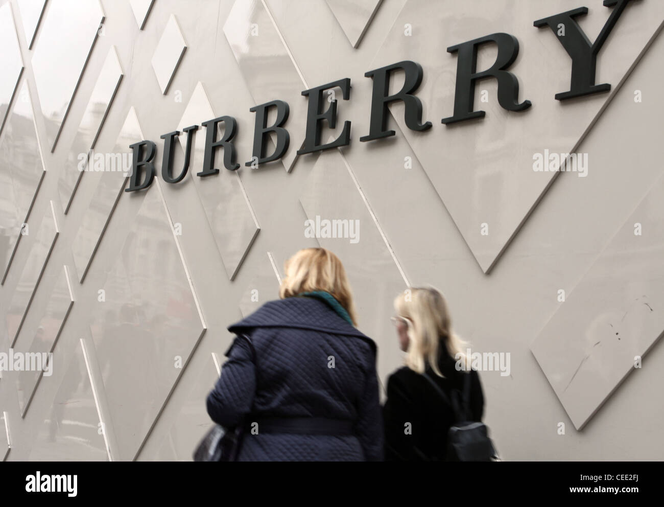 Two females walking passed a Burberry sign outside the Regent Street store Stock Photo