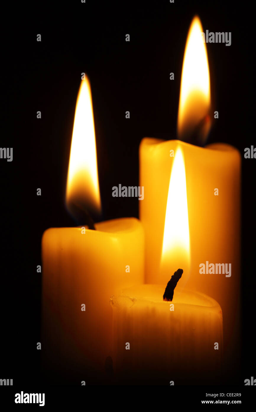 Three burning candles over a black background Stock Photo - Alamy