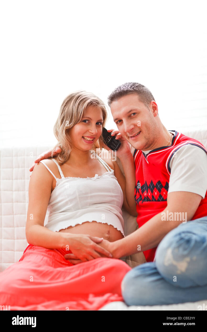 Happy pregnant woman with husband speaking mobile phone Stock Photo
