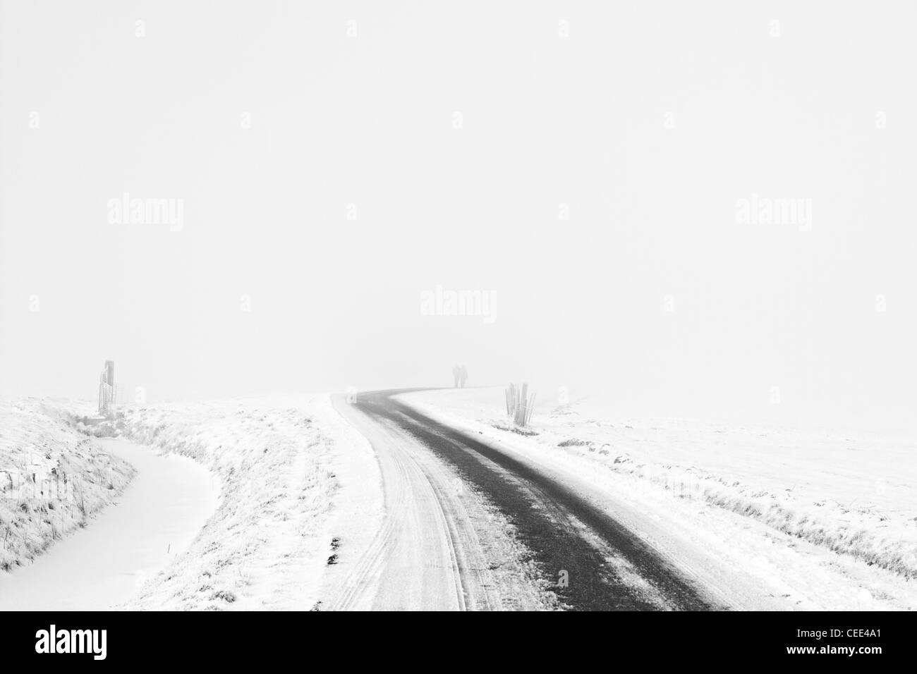 A couple walking on a lonely road in a white snow landscape Lisse Holland the Netherlands Europe Stock Photo