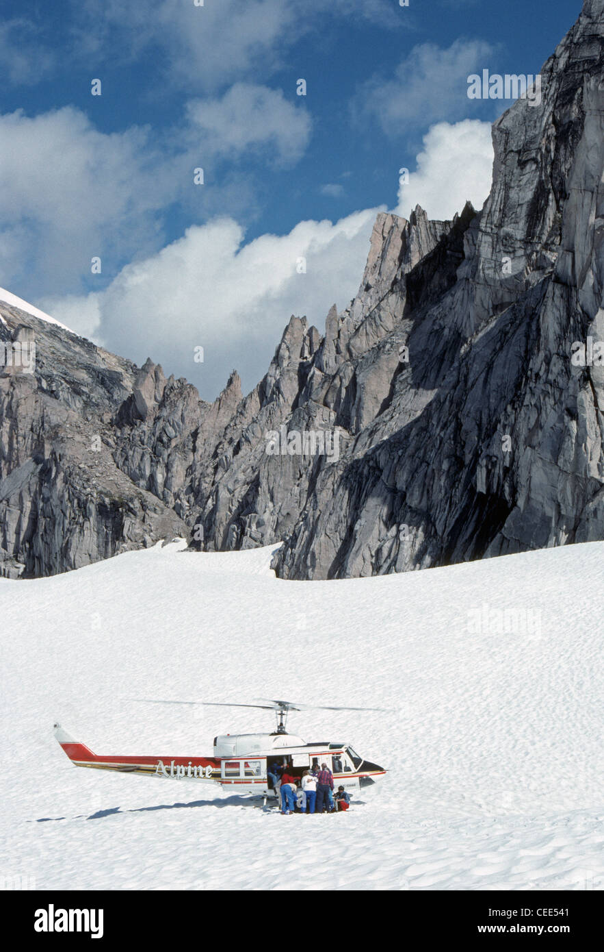 Hikers disembark from a helicopter on a snow-covered glacier in the Bugaboo range to explore the Purcell Mountains in British Columbia, Canada. Stock Photo
