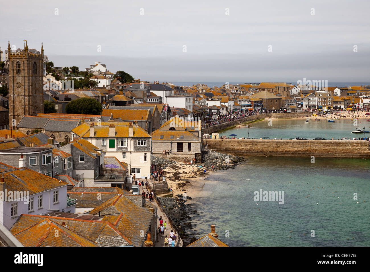 Church and rooftops at St Ives, cornwall,uk. Lichen covered rooftops, st ives harbour beach and granite stone jetty. Stock Photo