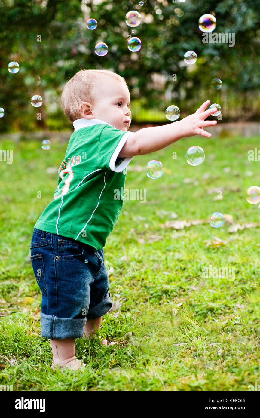 Little toddler boy reaching for soap bubbles in the garden Stock Photo