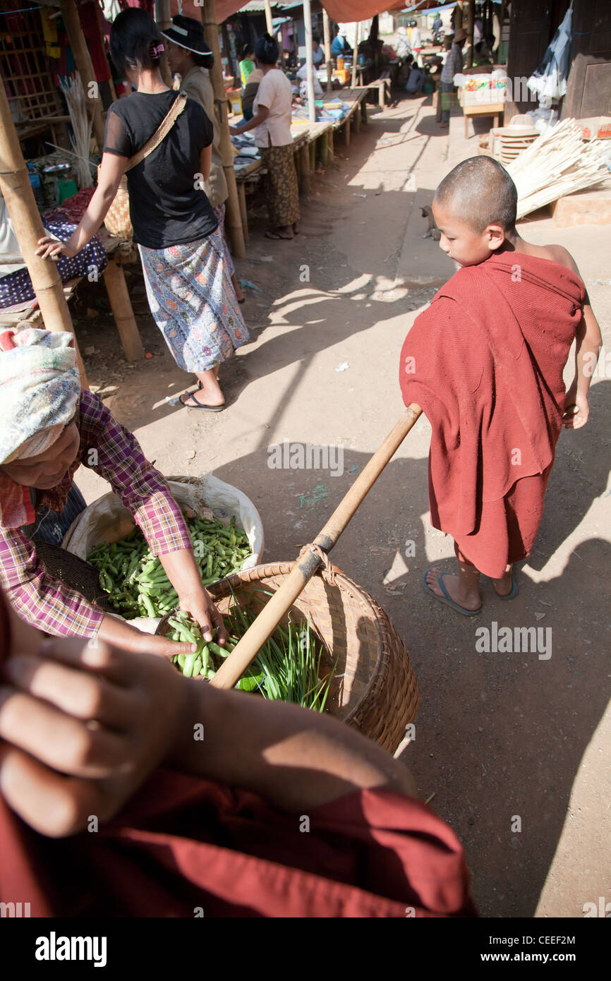 Monks are walking through the street market and receiving donations. Pindaya, Burma. Stock Photo