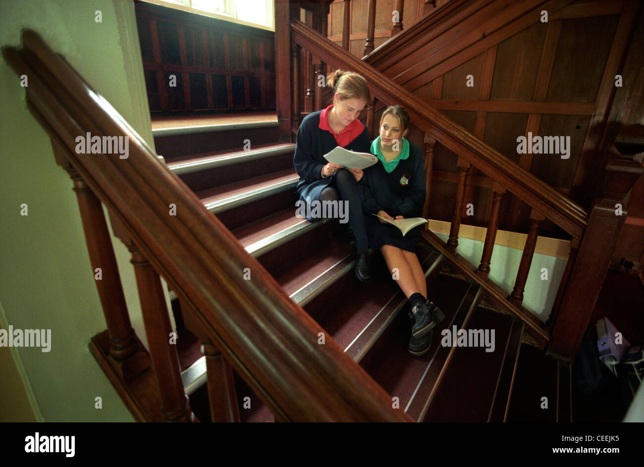 Two Roedean schoolgirl pupils compare notes in between lessons on the grand staircase. Stock Photo
