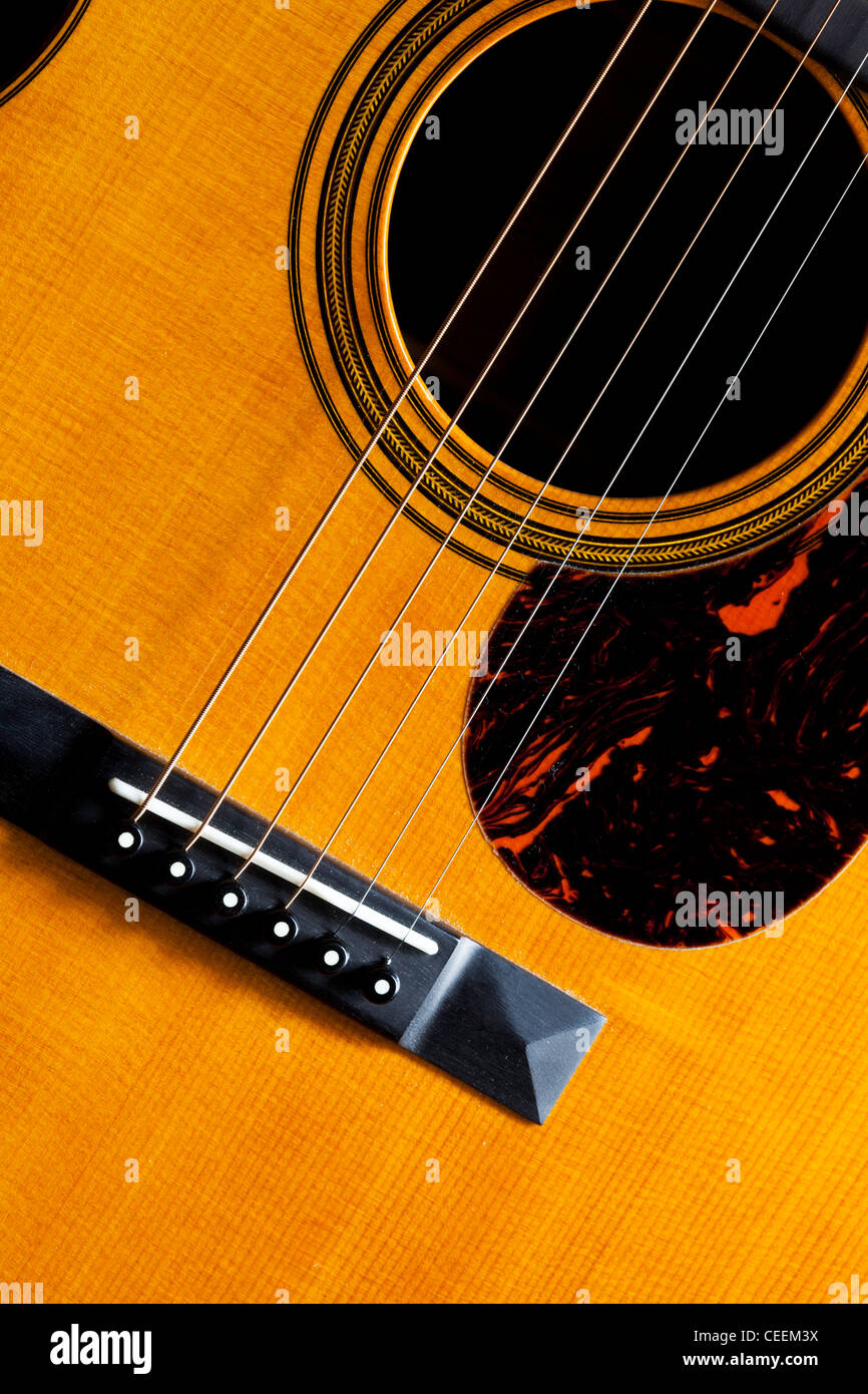 Detail of a Martin acoustic guitar showing the bridge, strings, scratch plate and sound hole. Stock Photo
