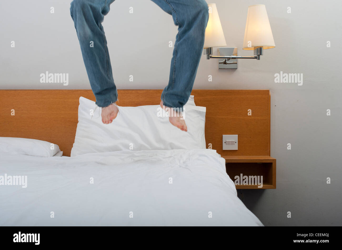 Bouncing on bed in hotel room legs in air above mattress. Stock Photo