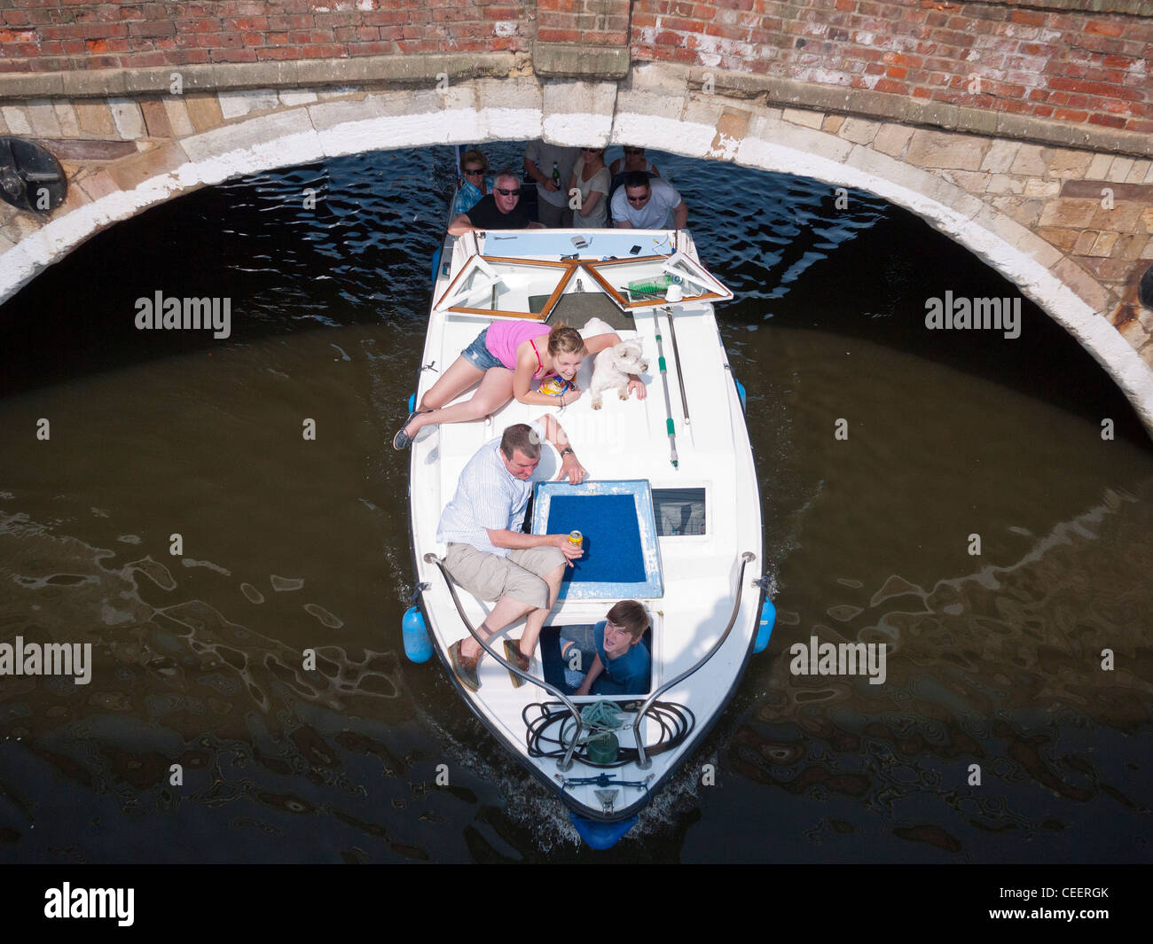People on a Hire Boat Passing under Bridge at Wroxham on the River Bure Stock Photo