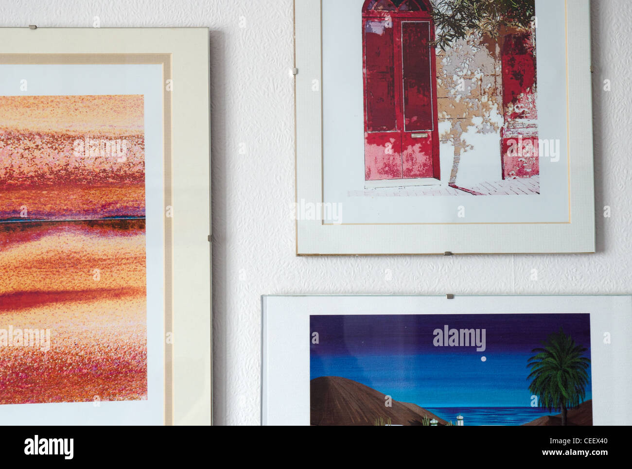 Framed pictures on a wall of a house with white wallpaper background