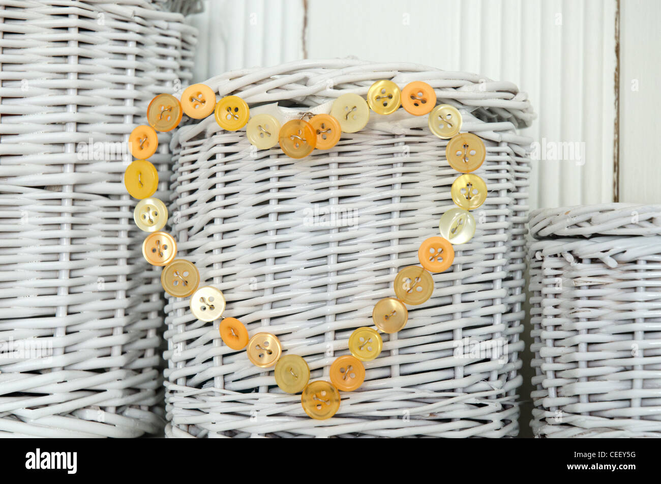 Heart shape made from yellow buttons against white painted wicker