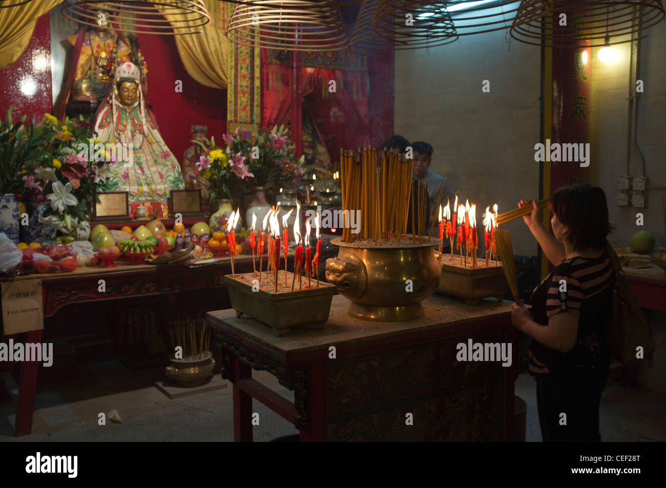 dh Man Mo Temple SHEUNG WAN HONG KONG Woman joss stick urns chinese shrine deity daoism altar burner sticks of incense Stock Photo
