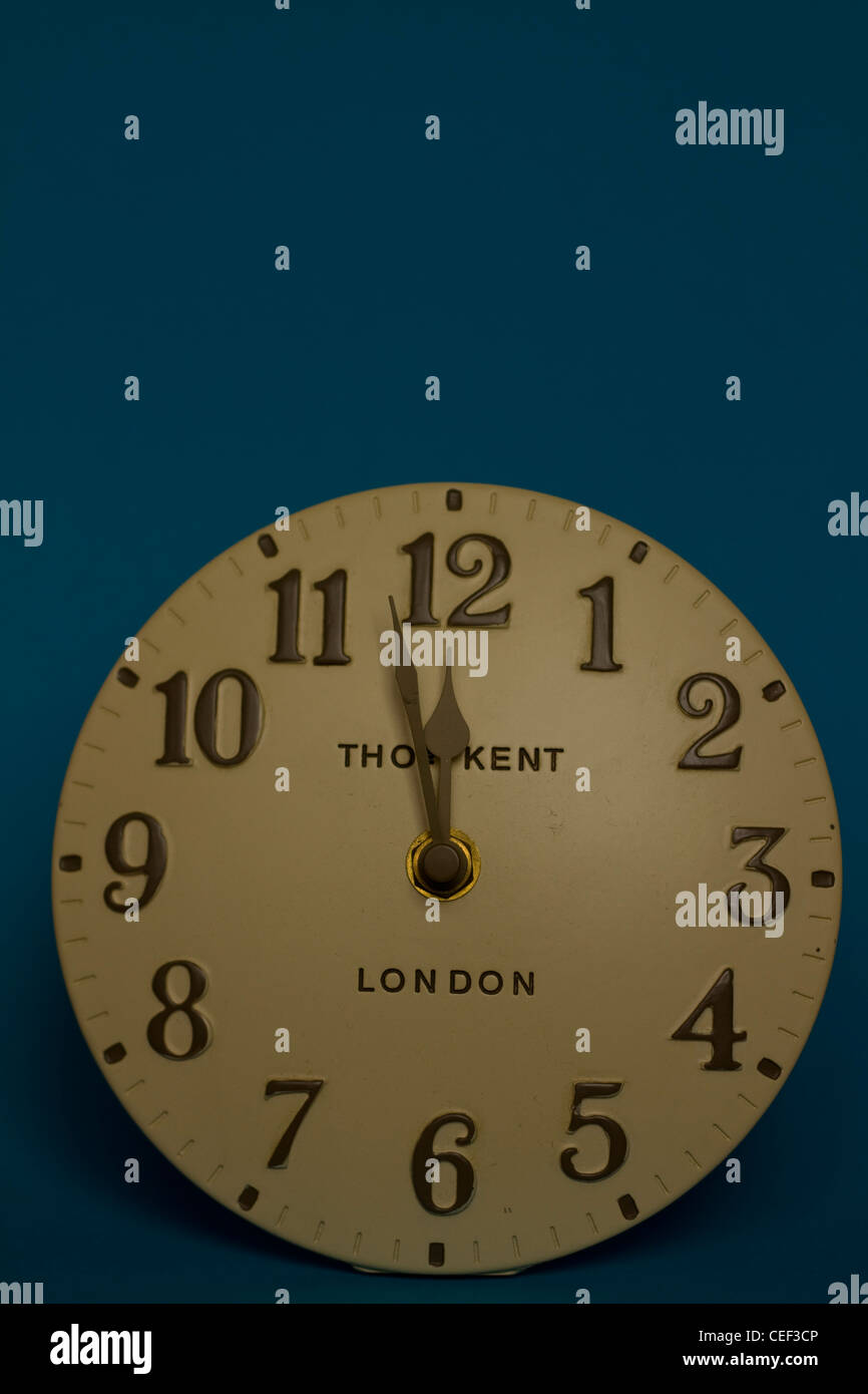 An oldfashioned analogue clock on a plain coloured background reads