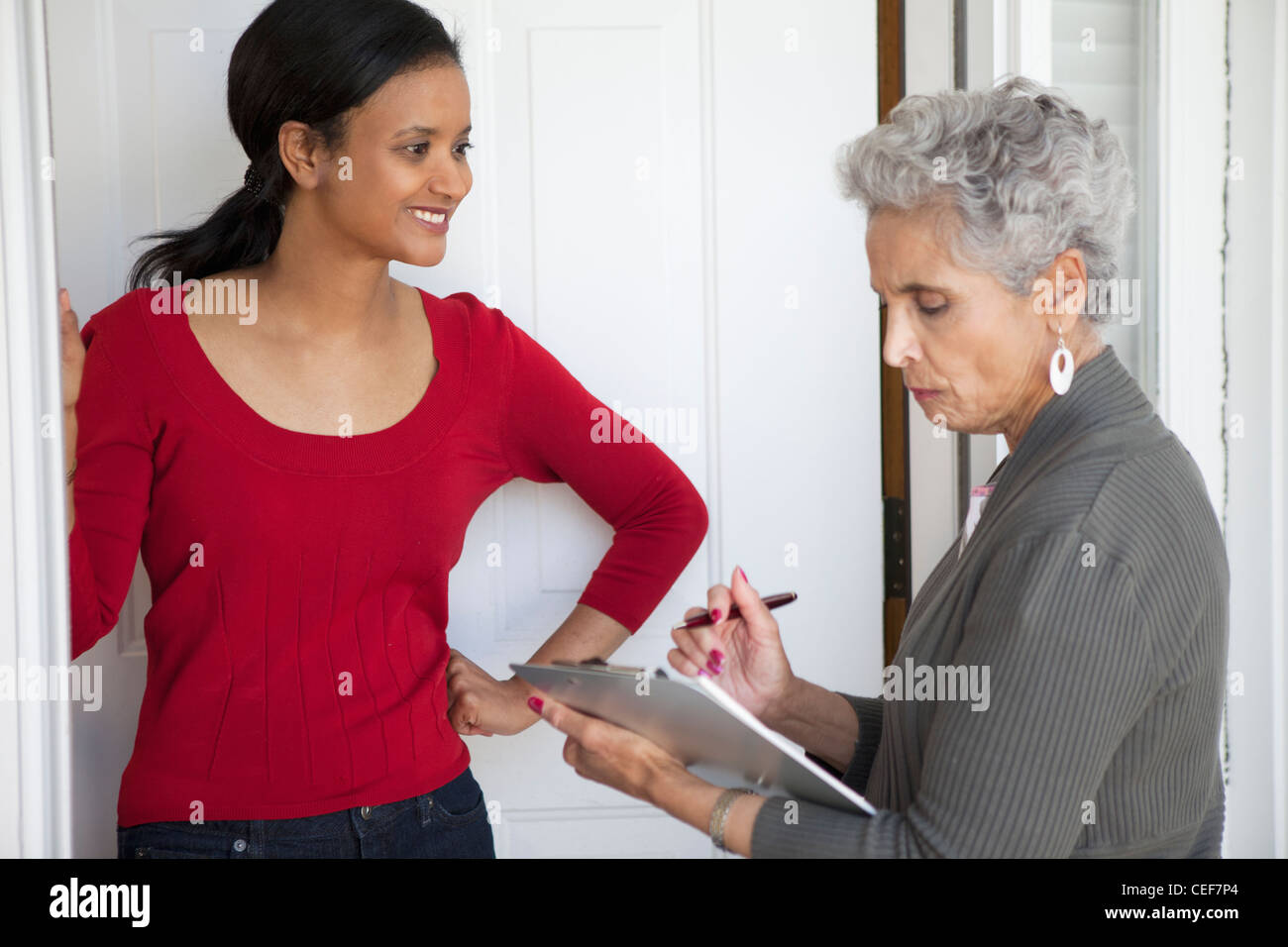 Black woman greeting a solicitor at her front door Stock Photo